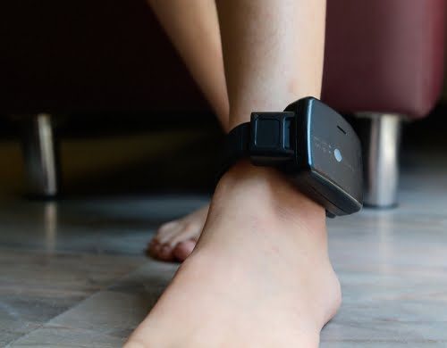 A person wearing and ankle monitoring device.