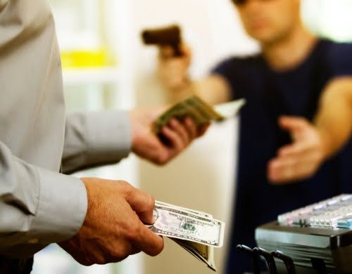 Man robbing a store demanding money from a cash register.